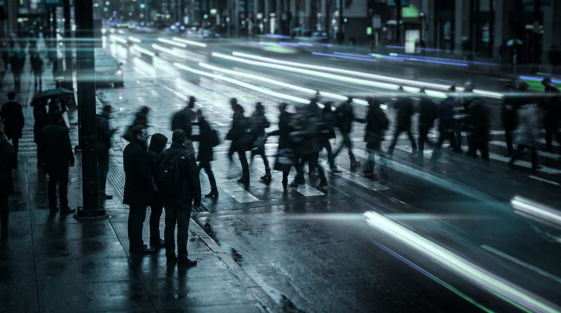 Avenida movimentada à noite com pessoas e rastros de luz teal